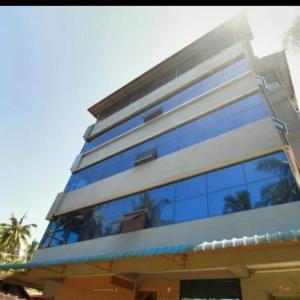 a tall building with blue glass windows on it at Hotel Kalyani International in Mūlki