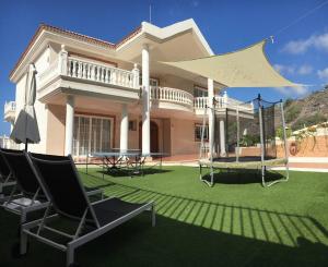 a house with a lawn with chairs and a swing at Villa Sunset View Tenerife, Simply Amazing in Adeje