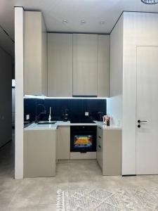een keuken met witte kasten, een wastafel en een open haard bij ARĞYN Apartments, 3-BR Central in Astana
