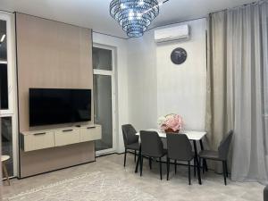 een eetkamer met een tafel met stoelen en een televisie bij ARĞYN Apartments, 3-BR Central in Astana