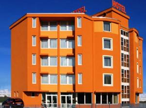 an orange building with a car parked in front of it at Hotel Verdina in Volpiano