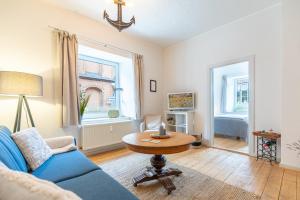a living room with a blue couch and a table at Eddies Hafenstuuv in Husum