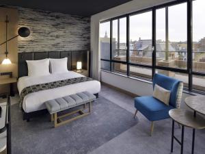 a bedroom with a bed and a table and a chair at Mövenpick Hotel The Hague in The Hague