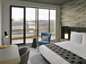 a hotel room with a bed and a chair and a window at Mövenpick Hotel The Hague in The Hague