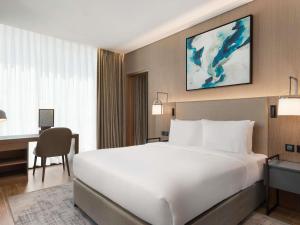 a hotel room with a large white bed and a desk at Mercure Dubai Gold District in Dubai +86 photos