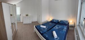 Un dormitorio con una cama azul en una habitación blanca. en Kuća Gabriele, en Ljubuški