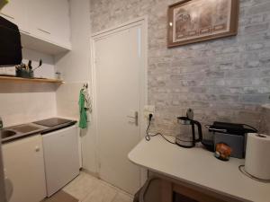 a kitchen with a white counter and a brick wall at Saint-Mandé studio, proche metro Ligne 1 & Paris Centre, Wifi rapide, Ideal couple, télétravail in Saint-Mandé