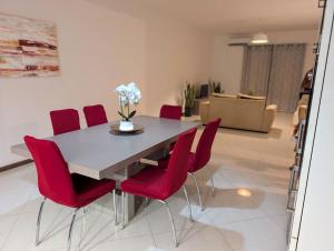 a dining room with a table and red chairs at Tabanka Azul - 2 BdR Cozy and Comfort Apt Near UN in Praia