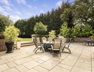 a patio with a table and chairs in a yard at Mayrose House - 6BR 4BATH Luxe Spacious Retreat in Takeley