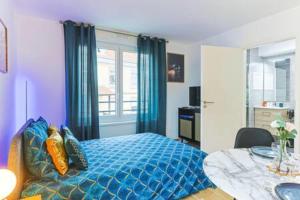 a bedroom with a blue bed and a table at Le Venise I Private Parking I Spacious & Bright in Colmar