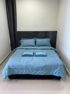 a bed with blue sheets and blue pillows on it at The Shore in Kota Kinabalu