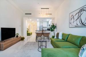 un salon avec un canapé vert et une cuisine dans l'établissement 1bedroom Apartment At Loreto, à Dubai Marina