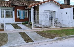 a white fence in front of a house at CasitaLibertad in Villa Augusta