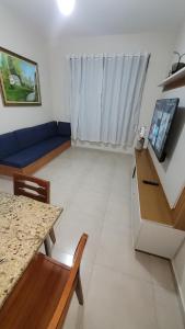 a living room with a blue couch and a table at Apto 3qts na Praia do Forte em Cabo Frio in Cabo Frio