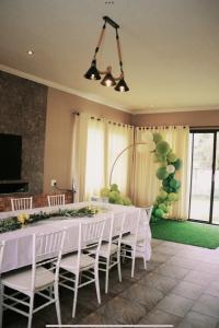 comedor con mesa blanca y sillas blancas en EastClaire Guesthouse, en Krugersdorp