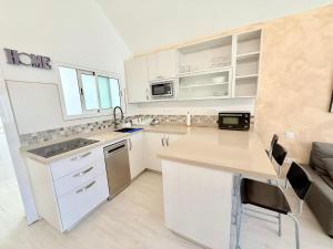 a kitchen with white cabinets and a counter top at Maspalomas Garden Bungalow with BBQ in Maspalomas