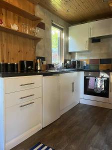 Una cocina con gabinetes blancos y una estufa. en Pine Marten Bar Glenmore Treehouse, en Aviemore