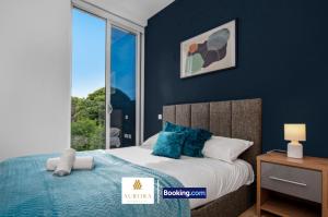 ein Schlafzimmer mit einem Bett mit blauen Wänden und einem Fenster in der Unterkunft Stylish 2BDR Apartment With Cinema, Gym and Free Parking By Aurora WorkNest Short Lets & Serviced Accommodation London in Kew Bridge