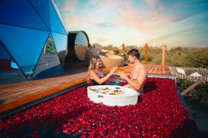 a man and a woman sitting in a tub of red flowers at Luxeglamp in Umm Al Quwain