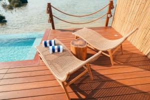 ウンム・アル・カイワインにあるLuxeglampのプールの横のデッキに椅子2脚とハンモック