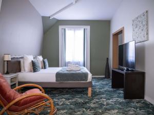 a hotel room with a bed and a television at Hotel Novotel Domaine de Maffliers - Paris Val-d'Oise in Maffliers