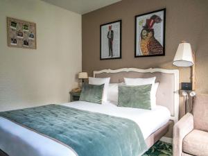 een slaapkamer met een wit bed en een blauwe deken bij Hotel Novotel Domaine de Maffliers - Paris Val-d'Oise in Maffliers +144 foto's