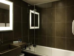Un baño con lavabo, bañera y espejo. en Novotel Lille Aéroport, en Lesquin 103 fotos más