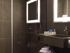 a bathroom with a sink and a mirror at Novotel Lille Aéroport in Lesquin +102 photos