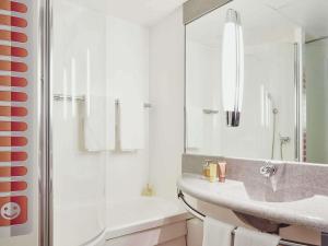 a white bathroom with a sink and a shower at ibis Styles Marseille Aéroport in Vitrolles +56 photos