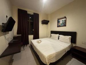 een slaapkamer met een groot bed en een televisie bij JJ Hotel Sitiawan Perak in Sitiawan