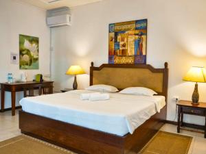 a bedroom with a large bed with two tables and two lamps at Villa Alizée - Boutique Hôtel Expérience - Idéal Couples & Pros - Piscine - Restaurant - Rooftop bar - Parking privé - 10min Port-Louis - Ambiance Tropical chic & authentique in Port Louis