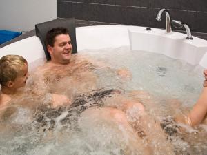 a man and two children in a bath tub at Luxury Villa with Pool - By Traum Ferienwohnungen in Marielyst