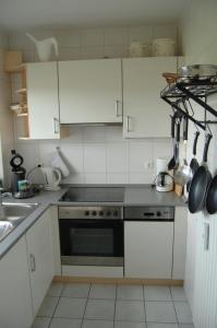 a kitchen with white cabinets and a stove top oven at Deichwohnung Strandweg 7 in Friedrichskoog-Spitze
