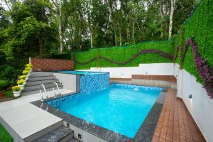 a swimming pool in a garden with a fence at Casa Bella, Thekkady in Thekkady