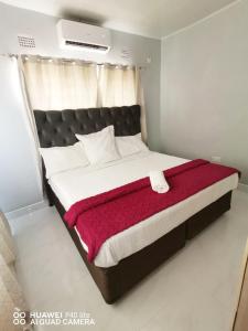a bedroom with a large bed with a red blanket at Wamz Apartments And Tours B in Livingstone