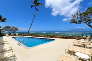a swimming pool with chairs and the ocean in the background at Kahana Reef 111 · KR 111 Renovated OceanFront Condo Romantic Get in Kahana