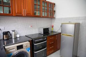 a kitchen with a refrigerator and a stove and a microwave at Maisara Apartment 2 in Zanzibar City
