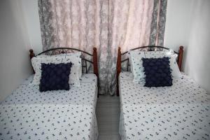 two beds with blue and white pillows in a bedroom at Maisara Apartment 2 in Zanzibar City