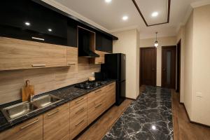 una cucina con armadi in legno, lavandino e frigorifero di Your Home Inn at Jikia's Green House-Central Tbilisi a Tbilisi City Altre 12 foto