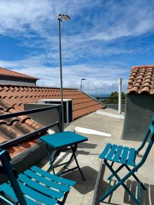zwei blaue Stühle und ein Tisch auf dem Dach in der Unterkunft Canto da Maré in Ribeira Grande + 3 Fotos