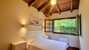 a bedroom with a white bed and a window at Apartamentos Rurales Senda Costera in Hontoria