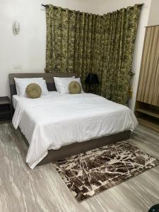 a bedroom with a large bed with white sheets and pillows at Bumcy Apartment in Ankuru