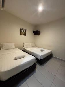 twee bedden naast elkaar in een kamer bij JJ Hotel Sitiawan Perak in Sitiawan