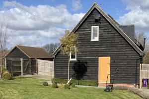 a black house with a yellow door in a yard at 1-Bed - Sleeps 2 - Pet Friendly w Parking in Hitchin