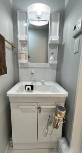 Un baño con un lavabo blanco y un espejo. en ゲストハウス, en Nagasaki 50 fotos más