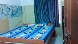 a bedroom with a bed with blue sheets and blue curtains at vks holiday homes in Malpe