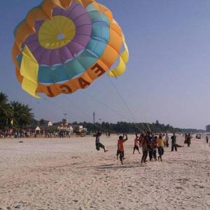 a group of people on a beach flying a large kite at vks holiday homes in Malpe