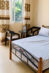 Lemba-GabaにあるCozy Guest Room in Kinshasa with Balcony and Partial Air-Conditioningのベッドと椅子2脚と窓のある寝室