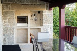 een hond die op een tafel voor een steenoven zit bij Casa Encosta do Monte in Póvoa de Lanhoso