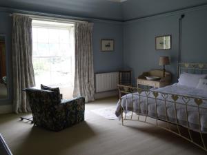 a bedroom with a bed and a chair and a window at Baysdale Abbey in Battersby